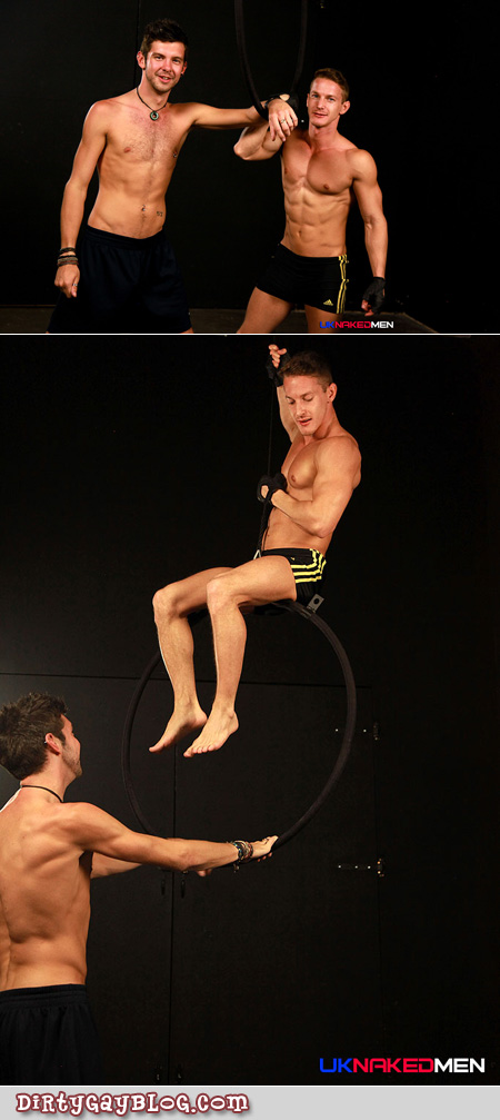 Muscular young men in athletic shorts try out a hanging hoop.