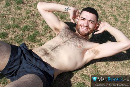 Hunky hairy-chested guy doing sit-ups in the park.